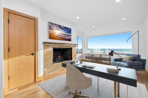 staged office with desk, fireplace and window with ocean view