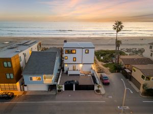 aerial view of rear side of home and sunset showing sand and ocean in background