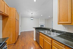 galley style kitchen at 219 Chaumont Lane, Foothill Ranch with wood tone cabinets and dark stone countertops