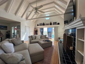 large and enclosed beachfront sunroom, gray couch and white ceilings