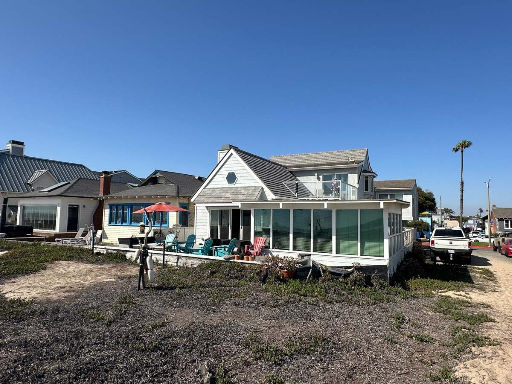 white beach house with large deck, blue sky in the background
