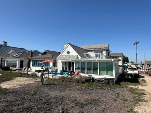 white beach house with large deck, blue sky in the background