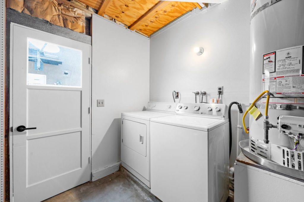 semi finished area in garage with washer and dryer and the water heater