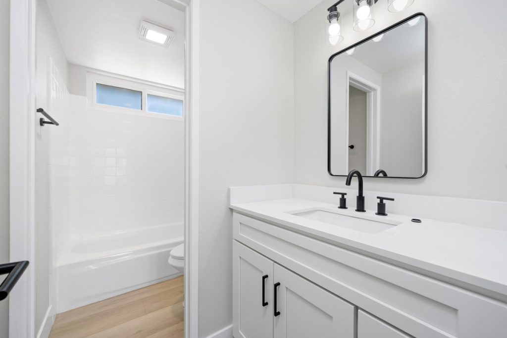 full bathroom with white cabinets and counters with black accents