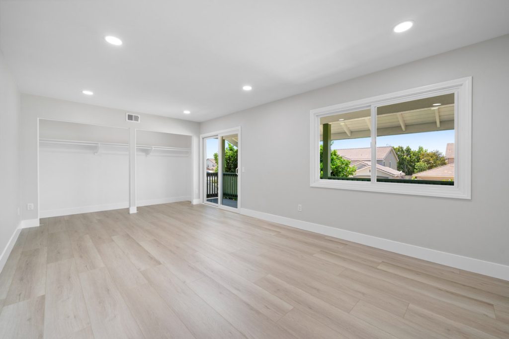 large empty bedroom with window and door leading to balcony
