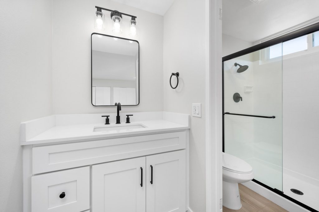 full bathroom with white cabinets and counters with black accents