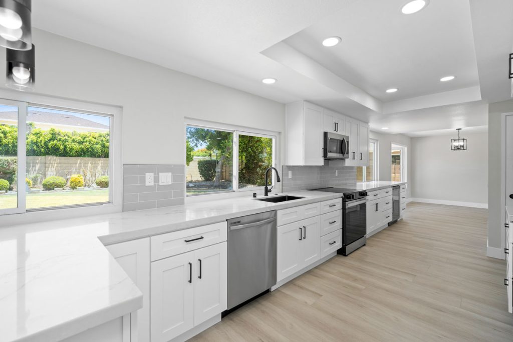 updated kitchen with white counters and cabinets and stainless appliances