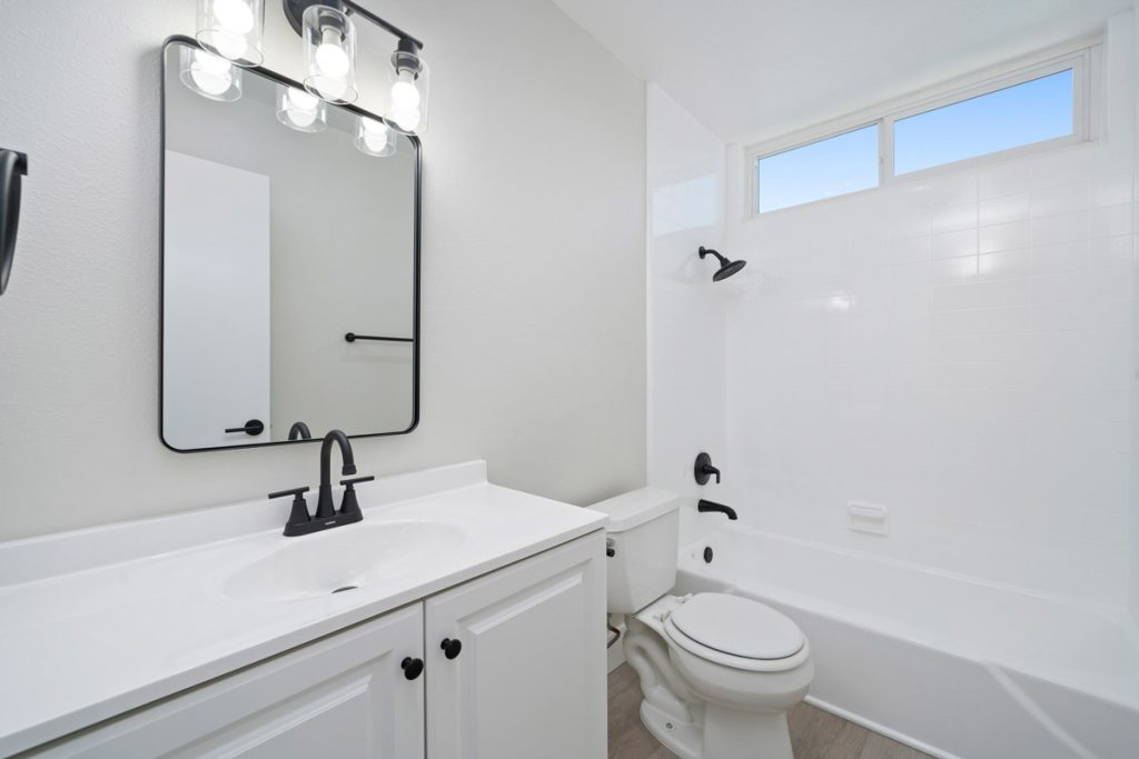 updated bathroom with white walls and vanity and black accents