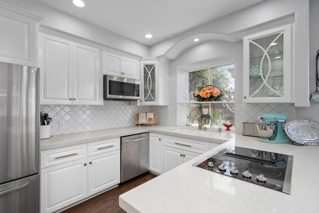 kitchen with white cabinetry white stone counters and stainless appliances.