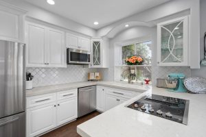 kitchen with white cabinetry white stone counters and stainless appliances.