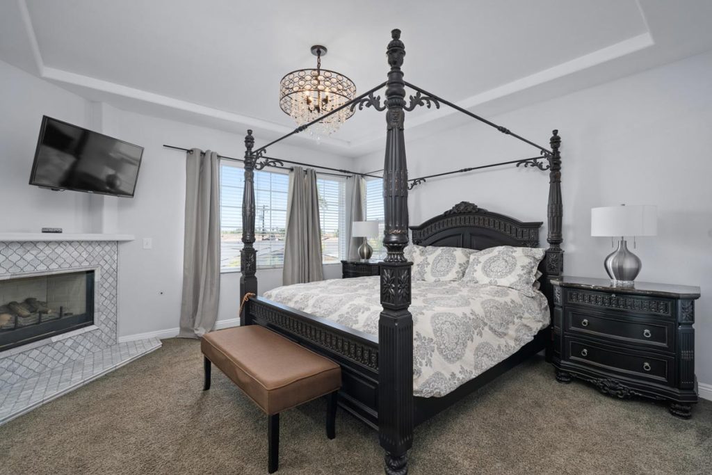 master bedroom with four poster bed, fireplace, mounted tv