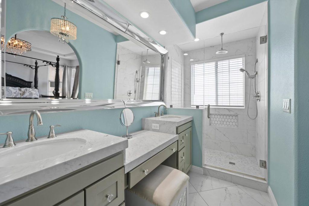 bathroom with teal colored walls, two separated sinks and a walk in shower