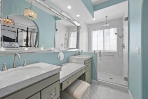 bathroom with teal colored walls, two separated sinks and a walk in shower