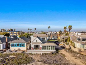 view of home on the sand with blue skies and palm trees in the background