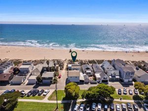 aerial view of beachfront home for rent with arrow pointing to home and sandy beaches with blue ocean in the background