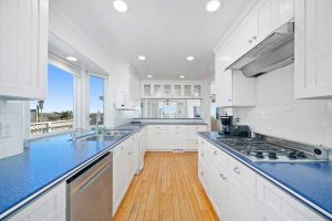 galley style kitchen with white cabinets, blue counters and windows overlooking beach