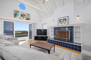 living space with couch, coffee table, and fireplace. Doors in background leading out to the beach