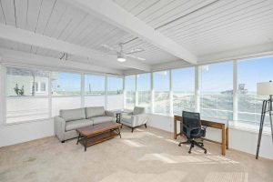 sitting room with walls of windows looking out to the beach and ocean