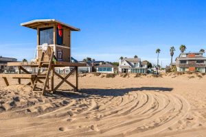 view of life guard tower at the beach with house for rent in the background