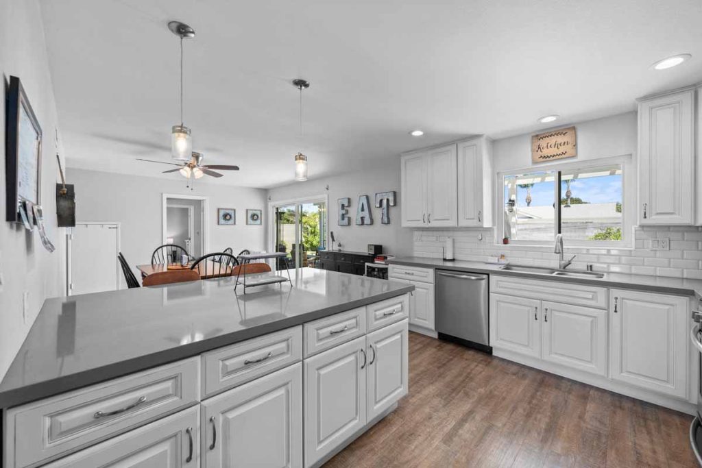 updated kitchen with white cabinets and stone counters.