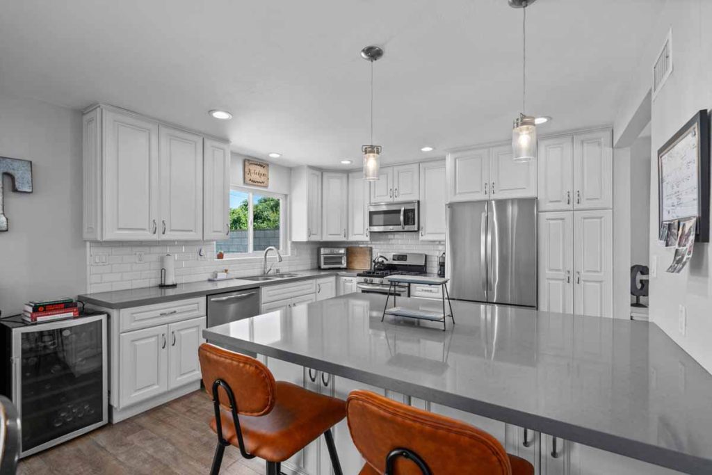 updated kitchen with white cabinets and stone counters.