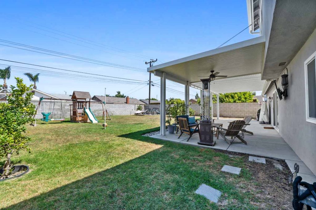 backyard showing grass, covered patio and play structure