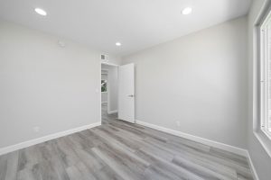 neutral empty bedroom with plank floors and recessed lights