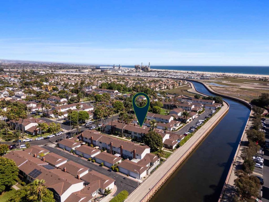aerial view of home for sale with arrow pointing to it. shows a canal and beach in the near distance