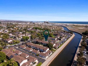 aerial view of home for sale with arrow pointing to it. shows a canal and beach in the near distance