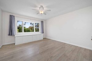empty bedroom with laminate floors, a large windows and a ceiling fan