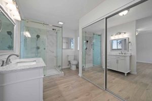 bathroom with sliding glass closet doors, glass-enclosed shower, vanity with sink, and a toilet.