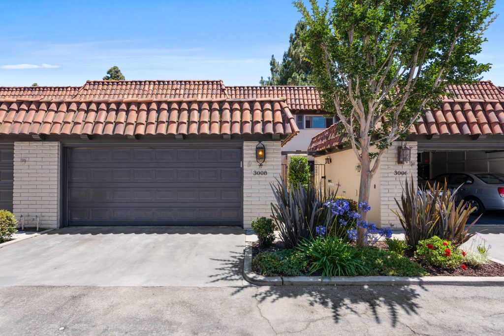 exterior of home for sale in costa mesa, showing cream colored stucco, brown garage door and terracotta roof tiles