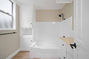 white shower and tub combo in a neutral bathroom with white cabinetry.