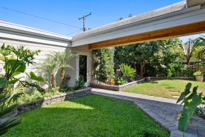 entryway to home with grass surrounding the walkway. There is a covered portion leading up to the front door.