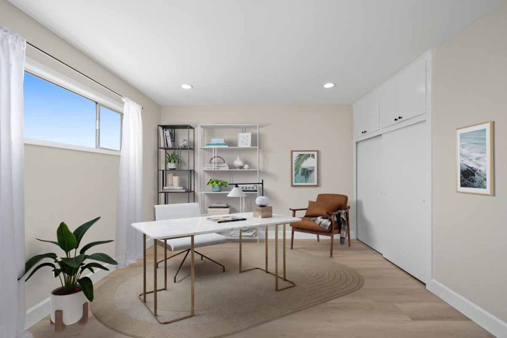 staged home office with minimalist desk on top of neutral flooring with a window and canned lights.