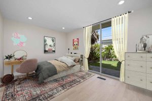 staged bedroom with a neutral color palate that has a sliding glass door to the backyard.