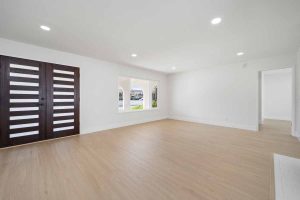 A large empty room showing the inside of the front door with vertical wooden slats.