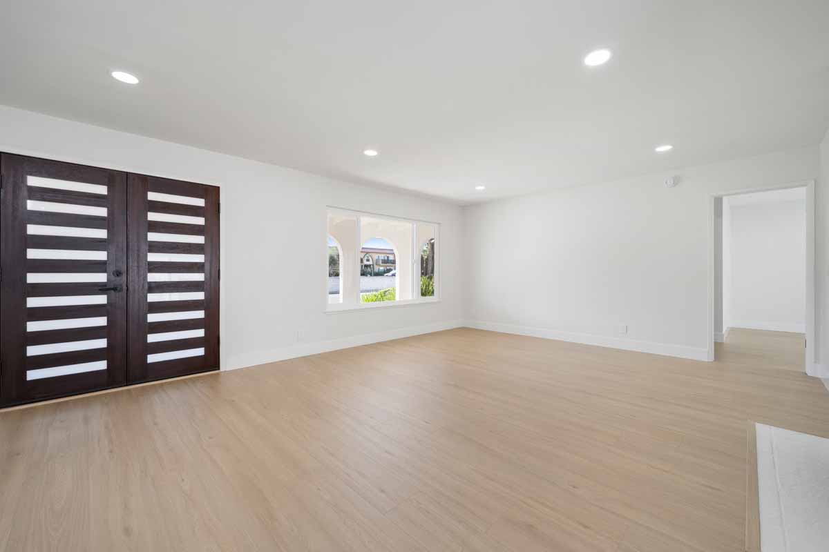 A large empty room showing the inside of the front door with vertical wooden slats.