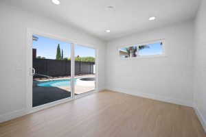 An empty master bedroom with sliding glass doors leading to the yard with a pool.