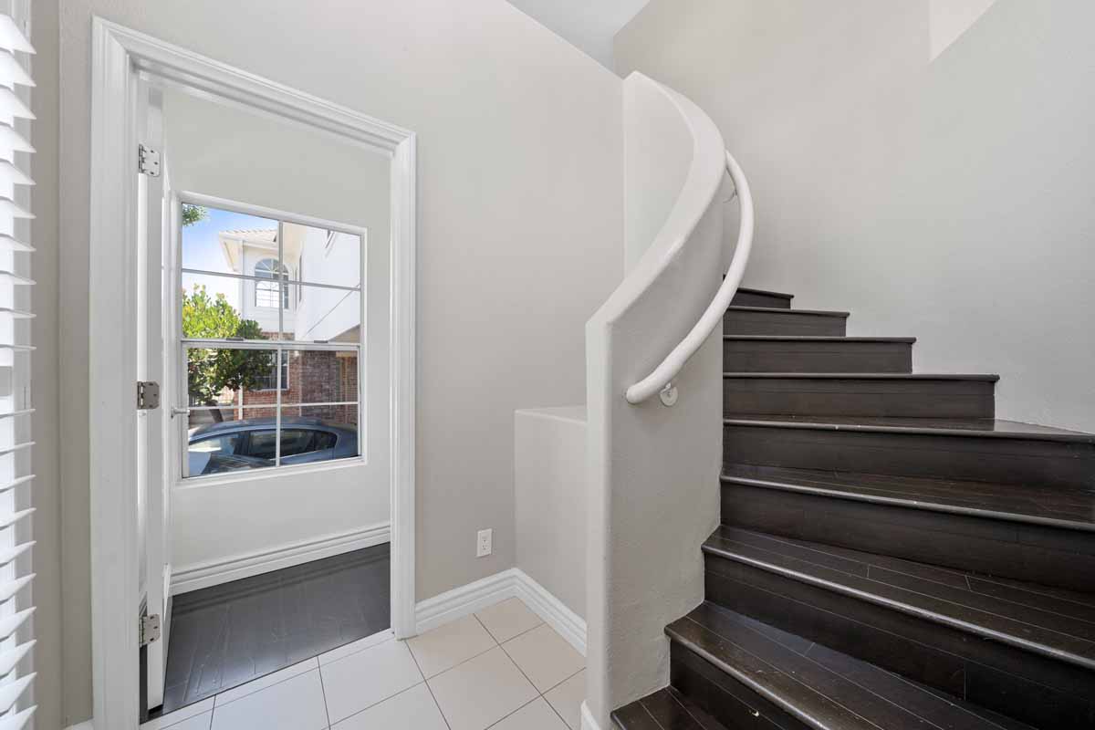 Light, neutral colored walls and a bright window with a stairway leading upstairs.