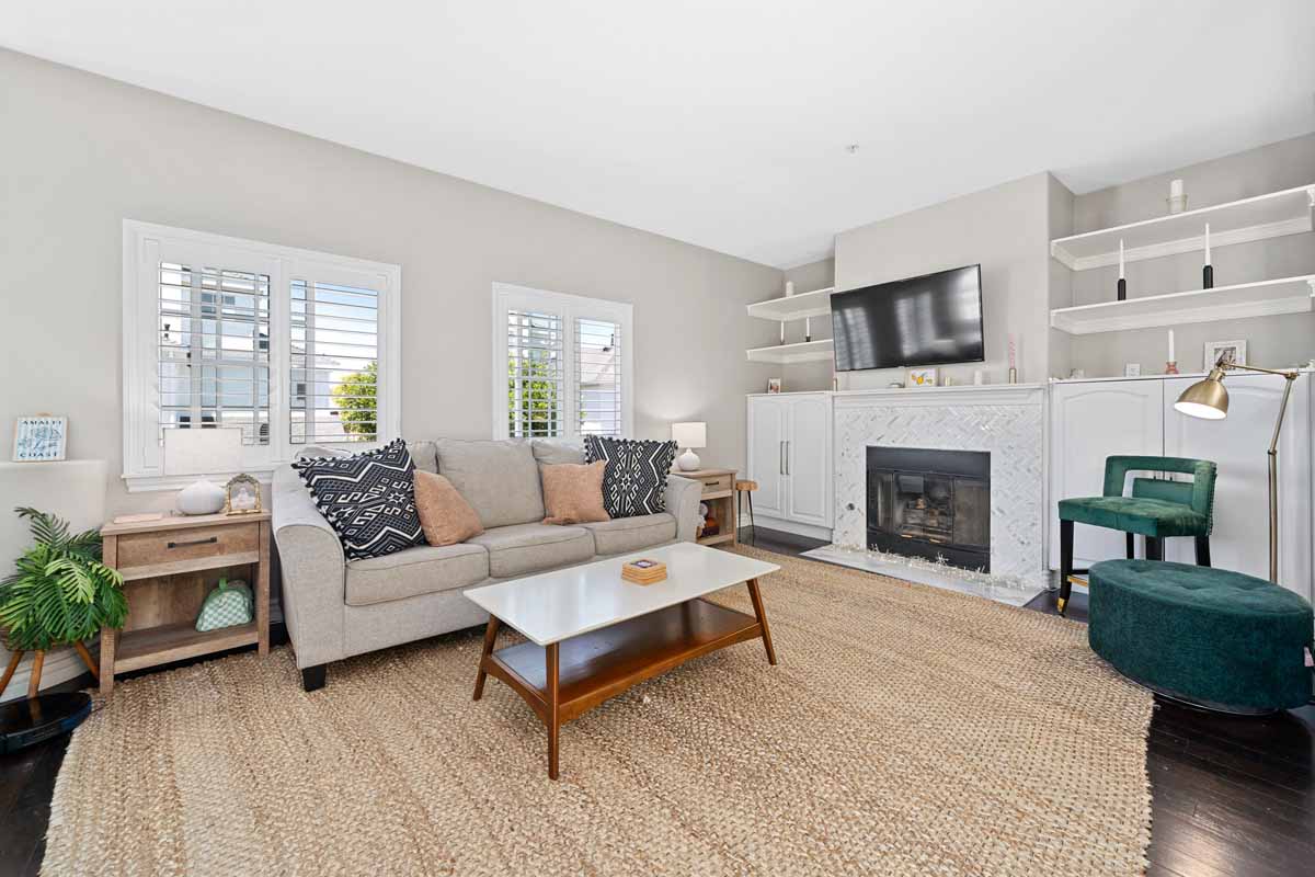 Living room with neutral wood flooring and walls with a couch, coffee table and fireplace.