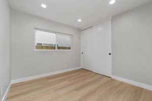 Bright white remodeled room with wood tile flooring, white walls, and a bright window.