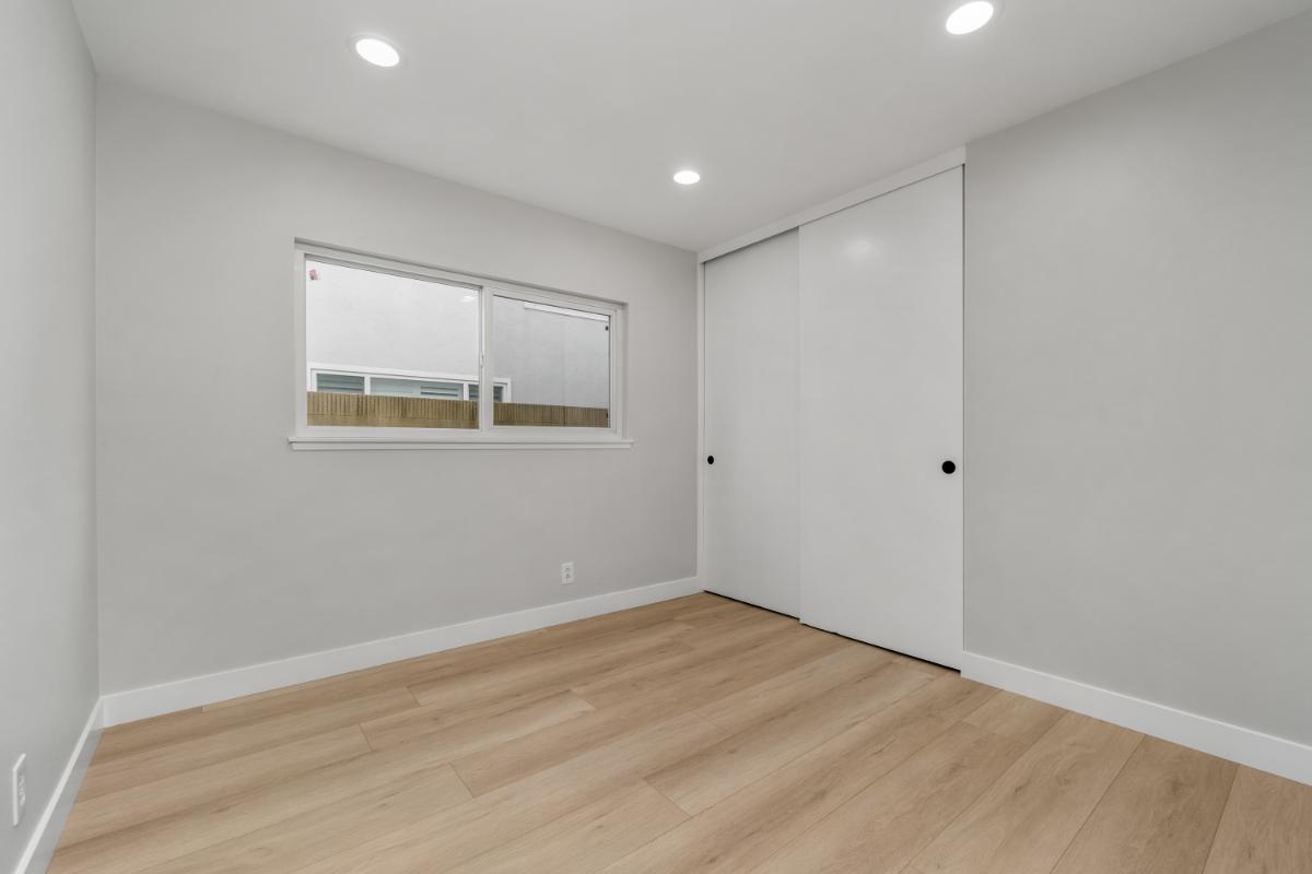 Bright white remodeled room with wood tile flooring, white walls, and a bright window. 