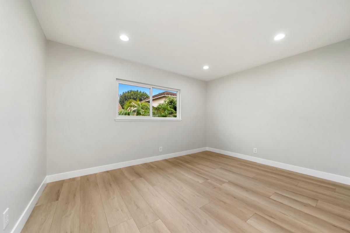 Bright white walls and new wood tile flooring. There is a small window on the far wall. 