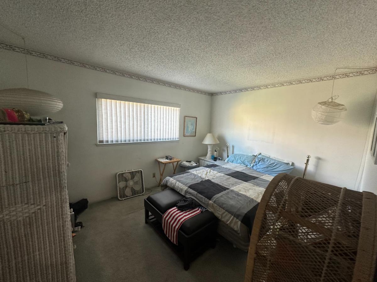 Dark bedroom with older carpet, older style decor. 