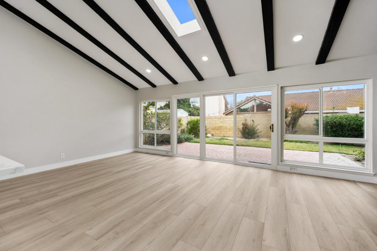 After of the remodeled sunroom with large windows, wood tile flooring, and bright white walls. 