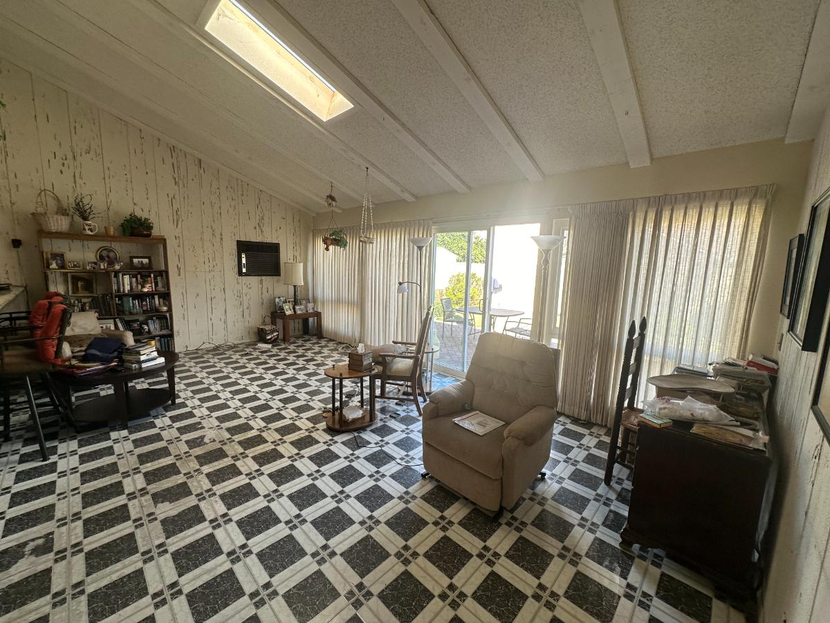 Before photo of a sunroom with vertical blinds, black and white flooring. 