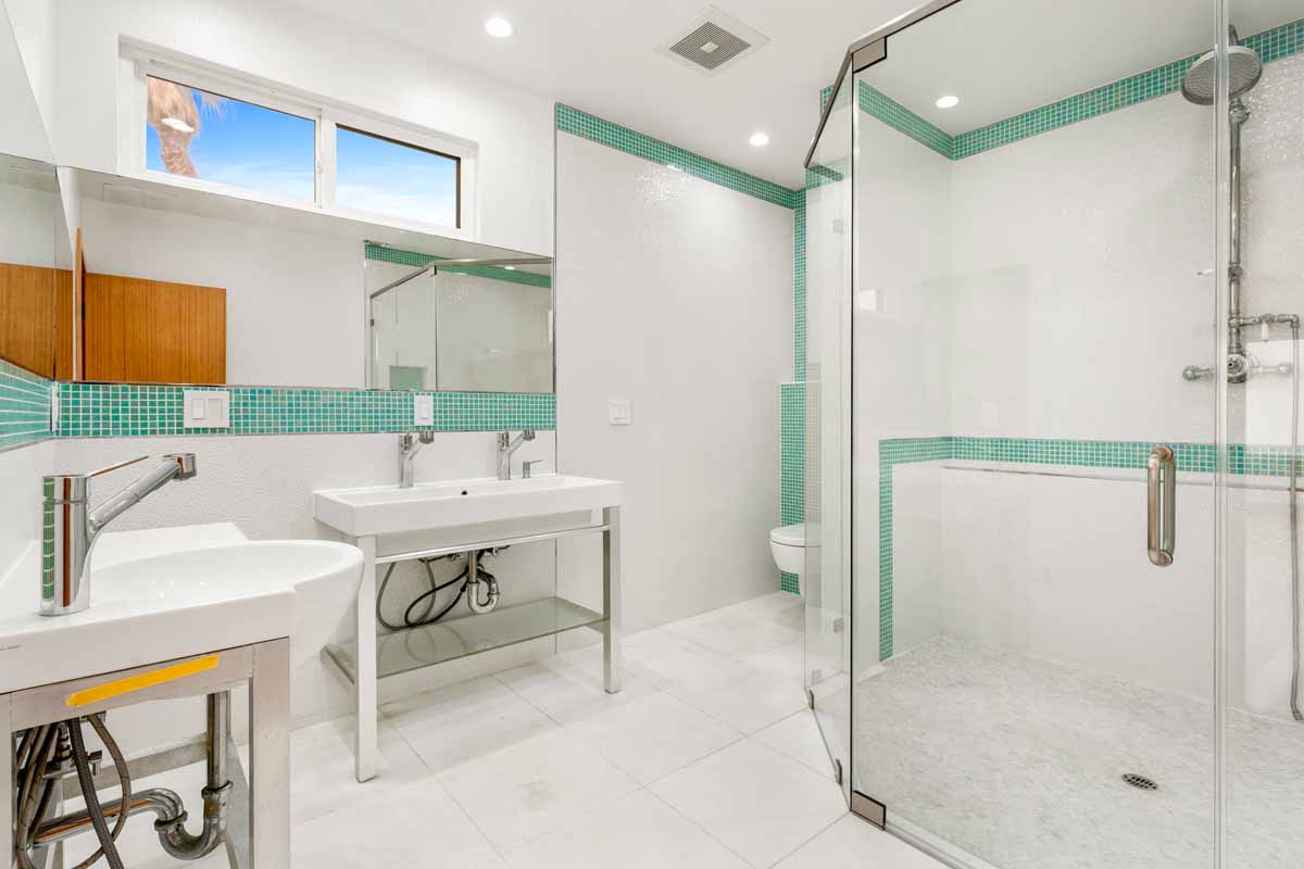 Updated bathroom with white and teal tiles and new glass shower door.