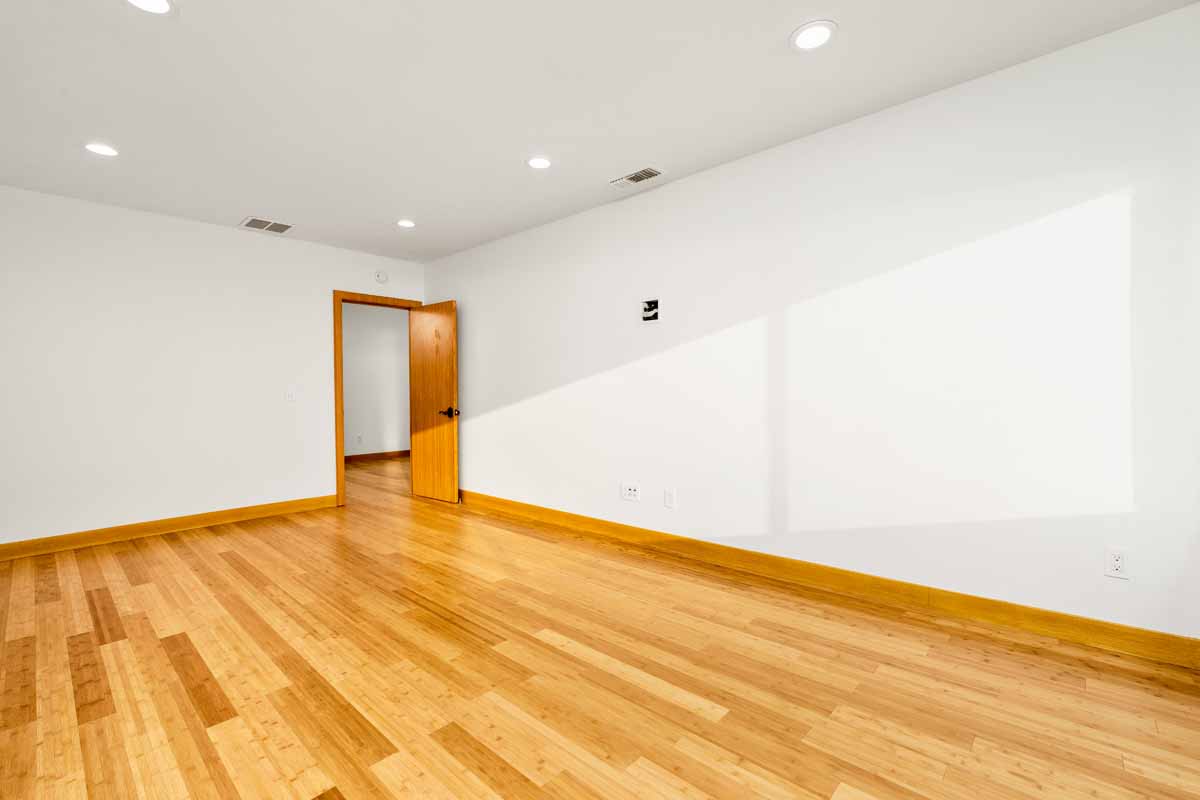 Updated, unfurnished bedroom with white walls and wood plank flooring.