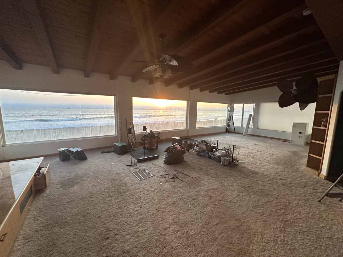 Large unfurnished master bedroom with a wall of windows overlooking the beach and ocean.